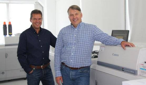 Two print service providers standing in front of a Canon production printer